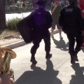 Saxofonista pone música de acompañamiento apropiada a policías antidisturbios