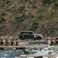 Porteadores transportan un coche con largos palos a través de una corriente en Nepal, 1948 (ENG)