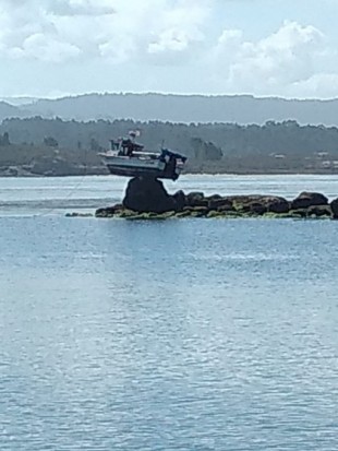 Un barco amanece suspendido sobre una roca de Punta Cabreira, en A Toxa