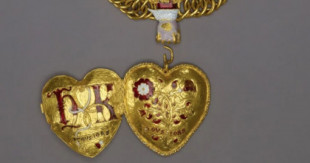 Aparece un medallón de oro con las iniciales de Enrique VIII y Catalina de Aragón