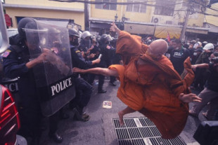 Un monje tailandés lanzando una patada a la policía durante una protesta. Noviembre de 2022