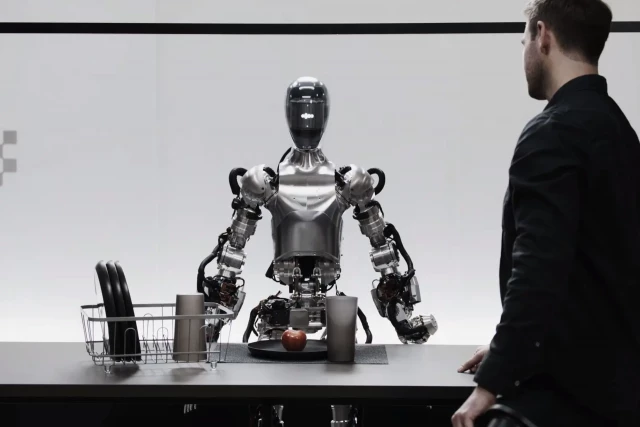 El plano se abre con el robot más avanzado hasta la fecha, un hombre y una manzana entre ambos. La conversación que tienen nos acerca a un futuro asombroso