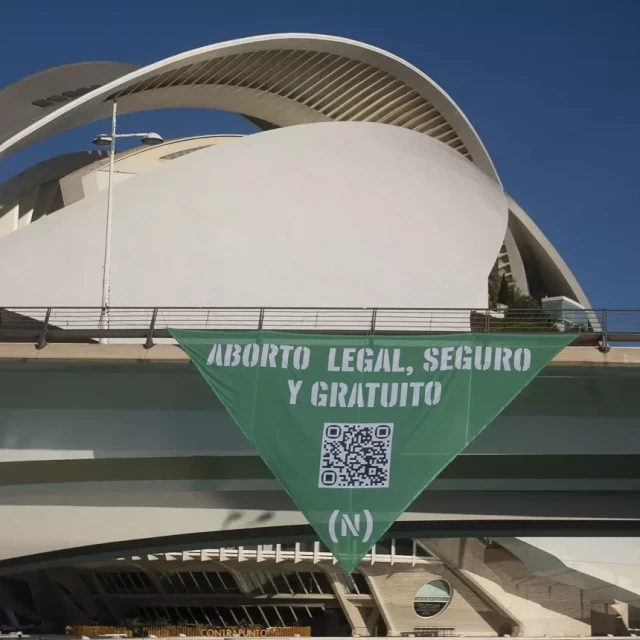 Un grupo de activistas descuelga un gran pañuelo verde en València en defensa del derecho al aborto