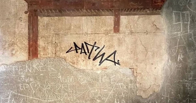 Un turista 'grafitea' la pared de una casa con frescos de hace varios siglos en la antigua ciudad de Herculano (Italia)