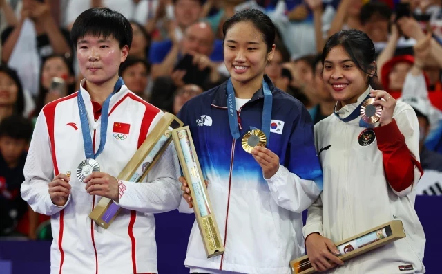 La deportista china He Bingjiao recoge su medalla con un pin con la bandera de España en homenaje a Carolina Marín